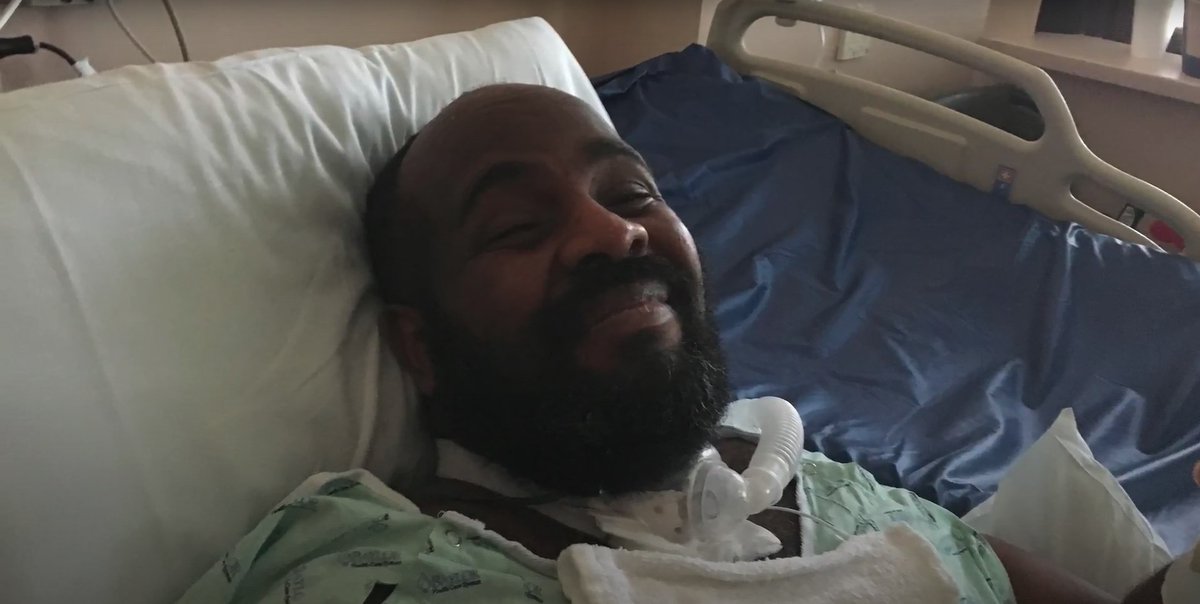 A black disabled man on an invasive ventilator smiling at the camera