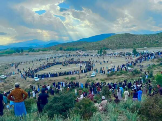 Picture of a mountainside range with hundreds of people scattered around watching cricke