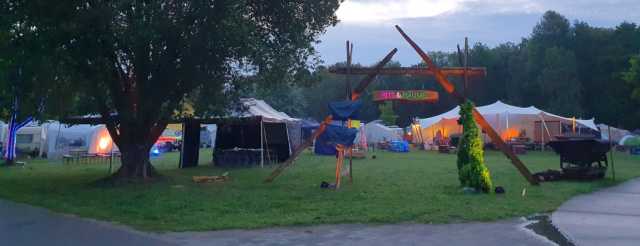 DE: Nach dem Gewitter der Nacht erwacht das Bits und Bäume Habitat gaaaaaaaanz langsam am Tag 1 des Chaos Camps 2023. Zu sehen ist ein hölzernes Eingangstor zum Habitat und dahinter das Vortrags- und das Workshopzelt.<br><br>EN: After the thunderstorm during the night, the Bits und Bäume (Bits and Trees) habitat slowly (very slowly) awakes. On the photo you can see the wooden gate to the habitat in the foreground and the tents for lectures and workshops in the background.