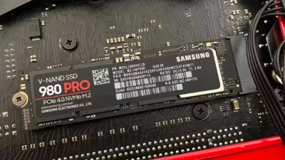 Close view of a motherboard showing just as SSD drive slotted into it. Text on drive card says V-NAND SSD 980 PRO PCIe 4.0 NVMe M2. Brand name says Samsung.