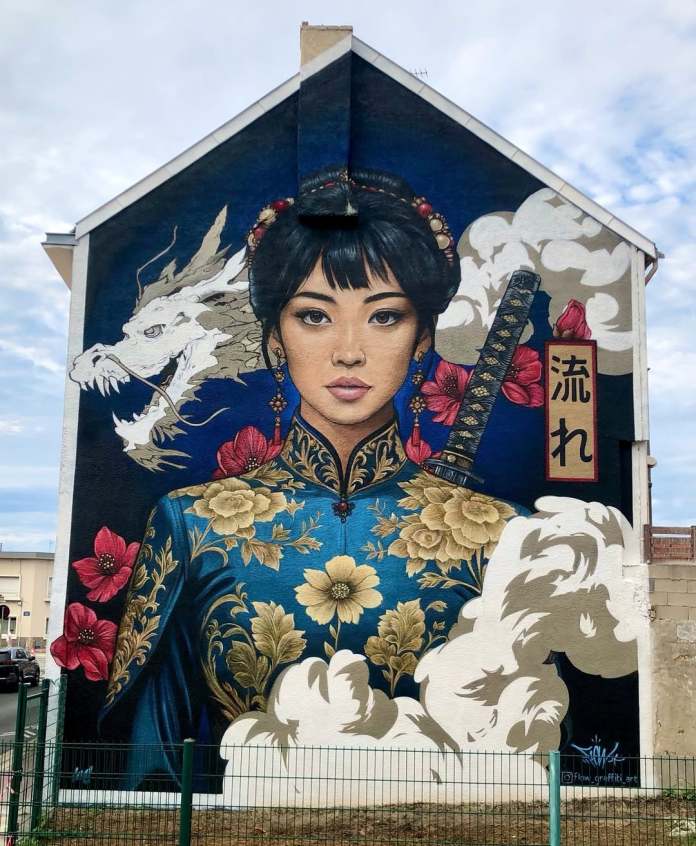 Mural by Flow Graffiti in Calais, France, showing a woman in ornate blue clothing with golden floral patterns, holding a sword with a white dragon behind her, framed by flowers and clouds.