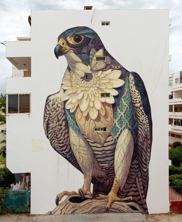 Mural of a falcon with flower petals and Moroccan-inspired textile patterns on its chest, painted on a tall white wall in Rabat, Morocco.