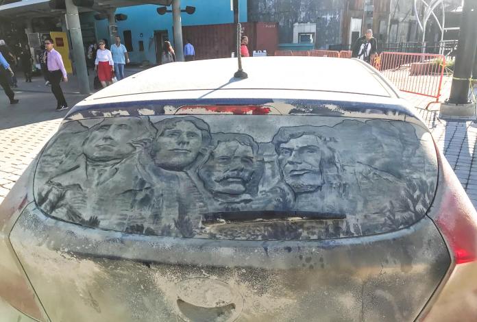 Grime art on the rear window of a dusty car, depicting the faces of the U.S. presidents carved into Mount Rushmore. The detailed artwork is etched into the dirt, accurately capturing the likenesses of George Washington, Thomas Jefferson, Theodore Roosevelt, and Abraham Lincoln. The car is parked in an urban setting, turning its back window into a tribute to American history.