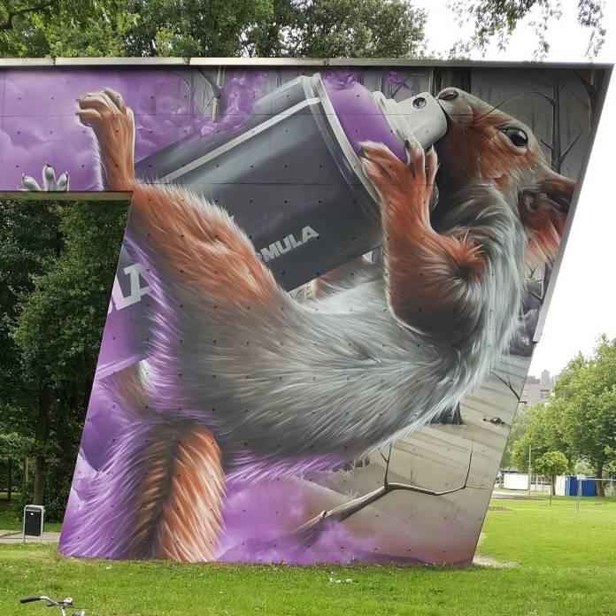 A mural of a playful squirrel gripping a large spray paint can, as though taking a sip from it, painted against a background of soft purple clouds. This whimsical artwork brings a sense of charm and humor, capturing the squirrel's curious expression and realistic fur detail. Created for a Street Art Festival in Belgium.
