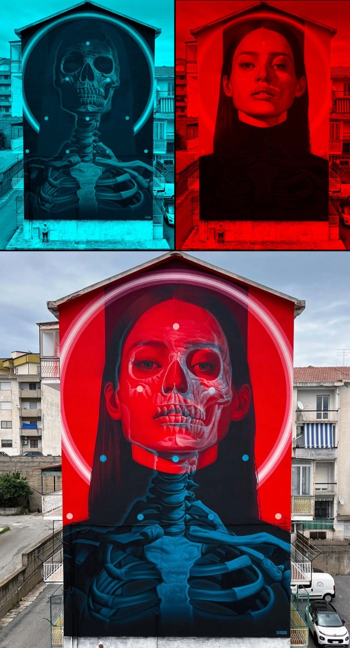 Mural covering entire side of a building in Crotone, Italy, showing a woman’s face in red with her skull and ribcage revealed beneath in blue hues. Created by street artist INSANE 51 using a double exposure technique.