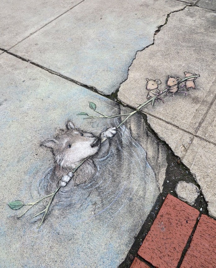 A whimsical sidewalk chalk drawing by David Zinn titled "The Rescue of Branimir by the Sjenica Sisters." The artwork blends seamlessly with the cracked pavement, depicting a small dog struggling in water, grasping a leafy branch held by three tiny mice working together to pull it to safety. The scene utilizes the pavement's natural cracks and textures to create depth, adding realism and charm. A red brick edge contrasts with the pale concrete, grounding the artwork in its urban setting.