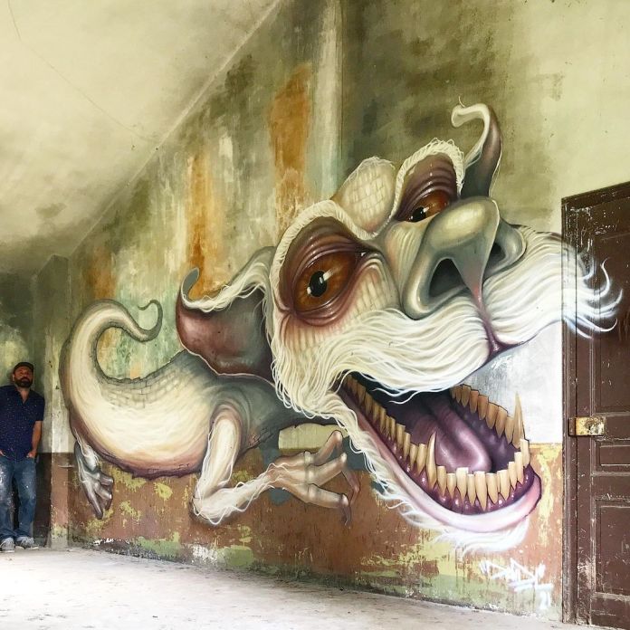 Post-graffiti artwork by DavidL featuring Falkor from The NeverEnding Story with detailed, exaggerated features and a whimsical expression, painted on a distressed wall with the artist standing nearby, located outside Barcelona, Spain.