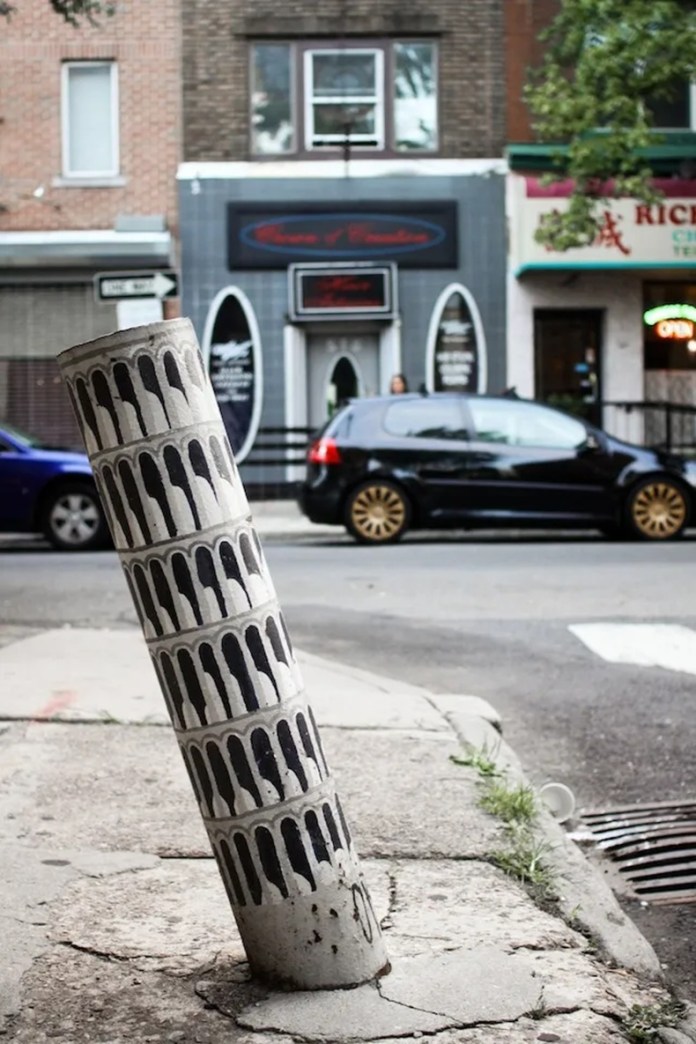 A tilted street pole humorously painted to resemble the iconic Leaning Tower of Pisa.