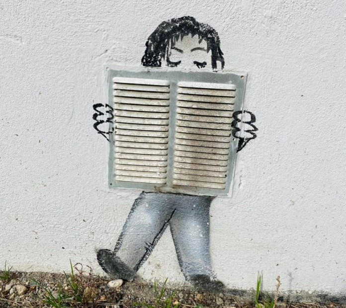 Street art showing a child playing an accordion, with a real wall vent used as the instrument. The child’s legs and head are painted on the wall, creating a playful 3D illusion.