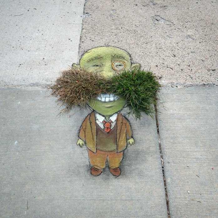 Sidewalk art by David Zinn of a green character named Leonard, wearing a brown suit and monocle, with two tufts of real grass forming a large mustache. The drawing is integrated into the pavement crack.