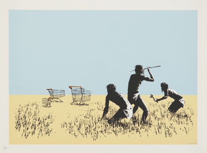 A Banksy artwork titled Trolley Hunters depicting three figures in a savanna-like landscape, crouched and armed with primitive tools, as they appear to hunt supermarket shopping carts. The scene satirizes modern consumer culture by juxtaposing prehistoric survival instincts with symbols of consumerism.
