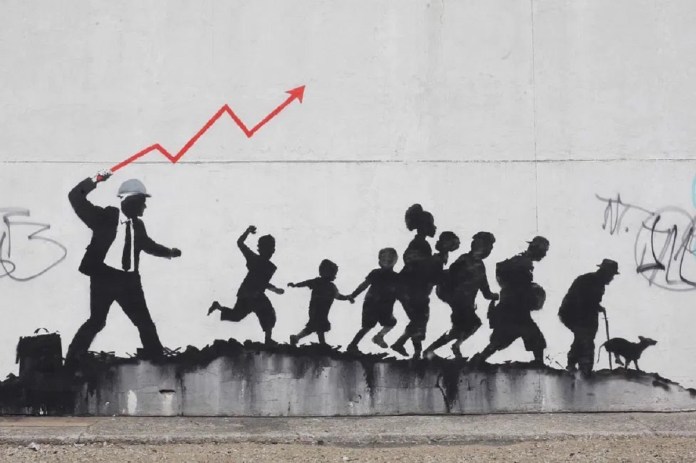 A Banksy mural showing a businessman in a suit and hard hat whipping a group of people with a red upward-trending graph line. The people, including children and elderly figures, are depicted as silhouettes walking on uneven ground, representing the exploitation of the masses for economic growth.