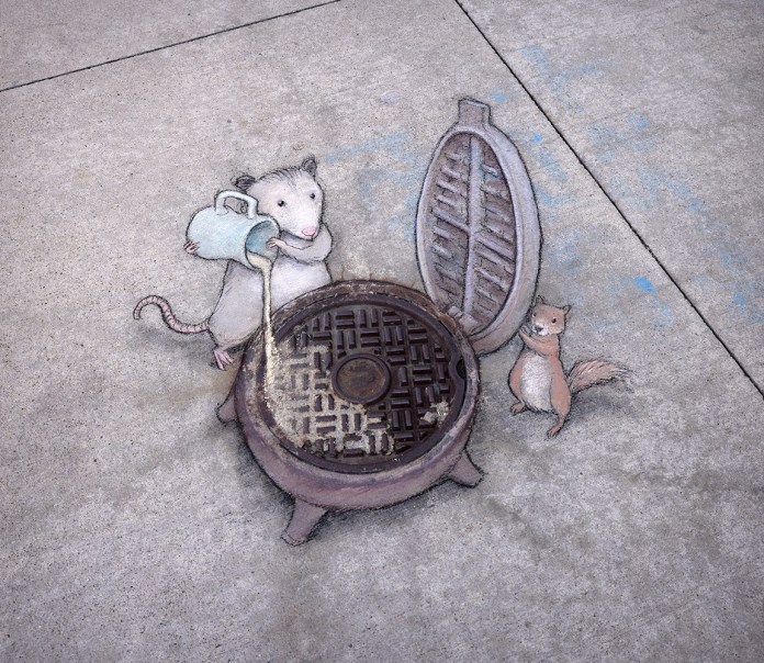 Chalk art by David Zinn shows a possum pouring batter into a manhole cover styled like a waffle maker, while a squirrel holds the lid open. The drawing uses the real cover’s texture as part of the design.