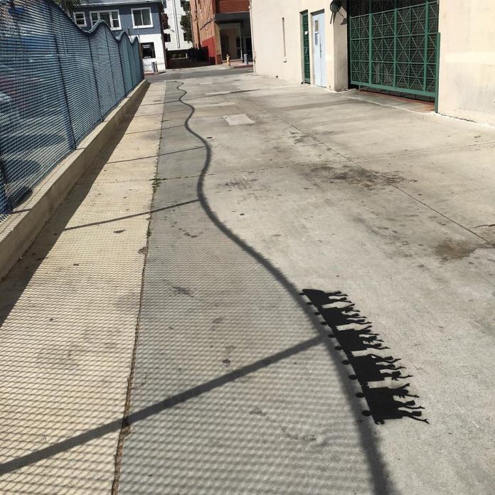 This street artwork by Tom Bob plays with shadow and light: the shadow cast by a mesh fence is enhanced by black silhouettes giving the illusion of people on a roller coaster.