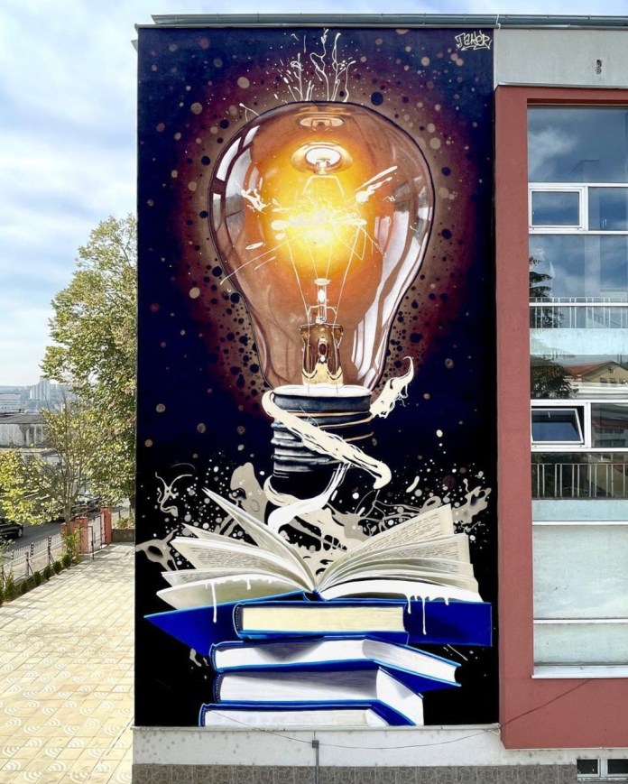 Mural by TAKERONE in Razgrad, Bulgaria, showing a glowing orange lightbulb erupting from an open book, with dynamic white paint splashes and stacked blue books below.
