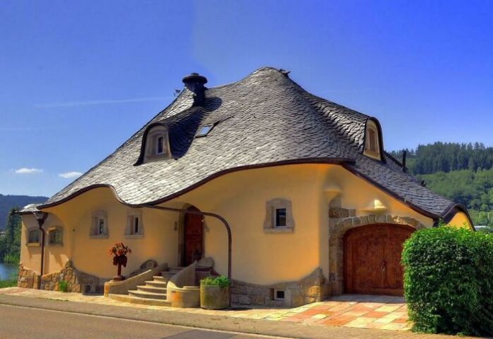 House in Germany with an undulating slate roof and rounded beige walls, resembling a whimsical cottage from a storybook.