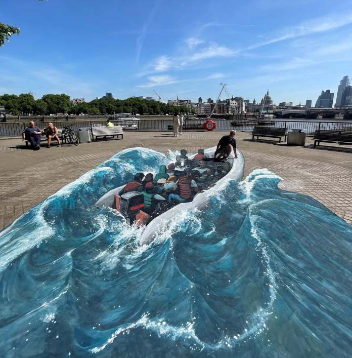 3D artwork titled “Boat in Rough Waters” showing a hyperrealistic inflatable boat filled with people on painted waves, blending into the surrounding pavement with city buildings and a river in the background.