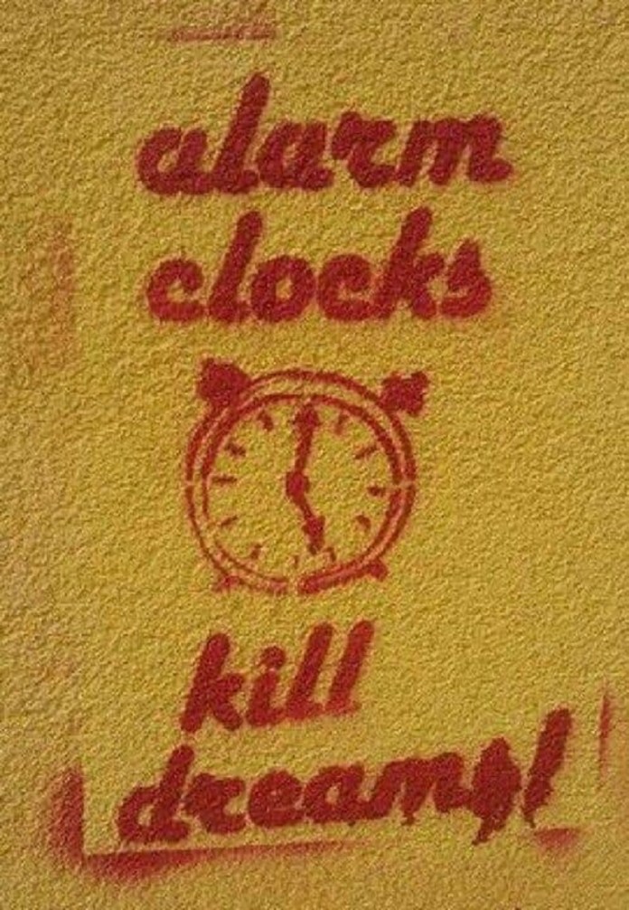 A red stencil on a yellow wall showing an alarm clock with the text “alarm clocks kill dreams!” in stylized, lowercase type.