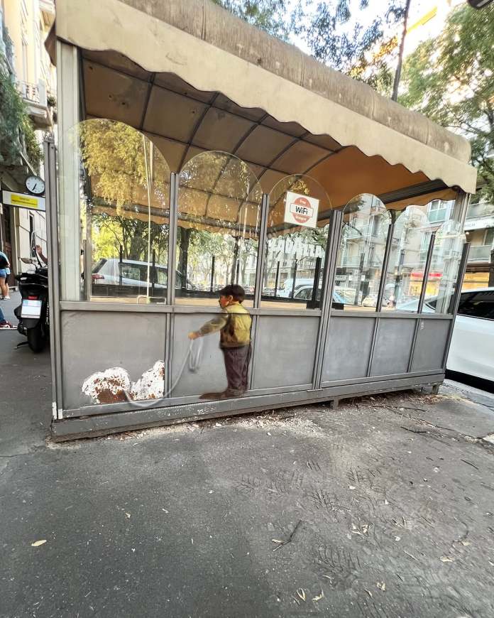 Street art of a boy walking a dog, with the dog’s form created using a rusted hole in a metal surface, appearing as part of the leash scene.