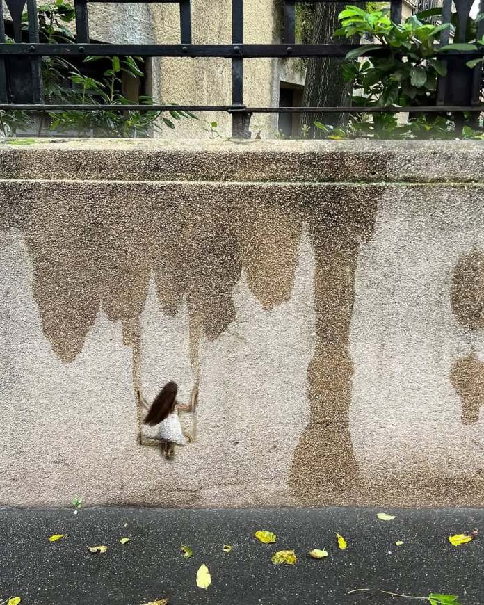 Girl on a swing, with water stains on the wall acting as swing ropes, blending natural marks with painted figure.