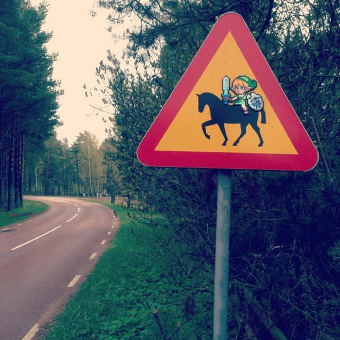 A triangular red and yellow warning road sign with a pixel art figure of Link from Zelda on horseback, holding a sword and shield, beside a winding forest road.