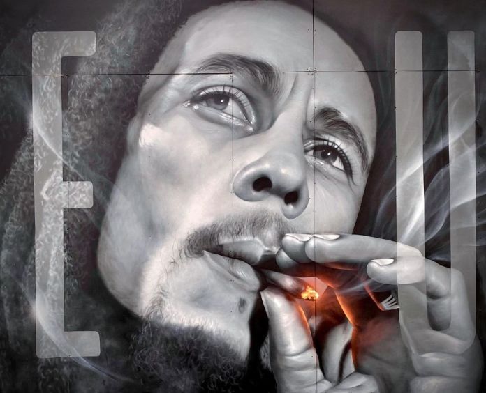 Photorealistic mural of Bob Marley smoking, captured in grayscale with glowing embers highlighting the cigarette.