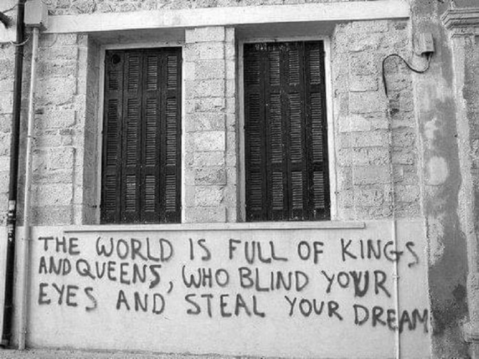 Black graffiti text quoting Black Sabbath lyrics on a building wall.