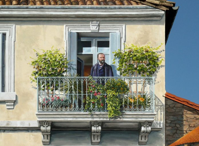 Detailed segment of Patrick Commecy's mural in Montpellier, France, showing a realistic scene of a man standing on a balcony framed by lush plants and intricate wrought iron railings. The man, with a well-groomed beard and dressed in a dark jacket, gazes thoughtfully outward, surrounded by vibrant greenery and flowers, including ivy and small fruit-bearing plants. The building’s architectural details are finely painted, from the textured walls to the tiled roof above. This mural skillfully integrates realism and artistry, blending the painted figure seamlessly into the structure.