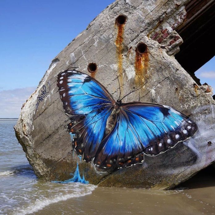 Graffiti mural by Näutil of a blue butterfly at a beach
