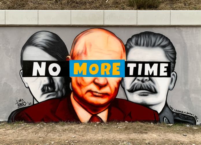 A striking mural by Polish street artist Piotr Tuse Jaworski, known as TUSE, displayed outside the PKM Gdansk Jasien railway station. The artwork juxtaposes the faces of Vladimir Putin, Adolf Hitler, and Joseph Stalin, symbolizing tyranny and oppression throughout history. Across their eyes is the bold slogan 'No More Time,' with the words 'No' and 'Time' in black against white, and 'More' in blue and yellow, the colors of the Ukrainian flag. This mural is part of a series of 'Solidarity with Ukraine' artworks in Gdansk, emphasizing the urgency to end war and support peace.