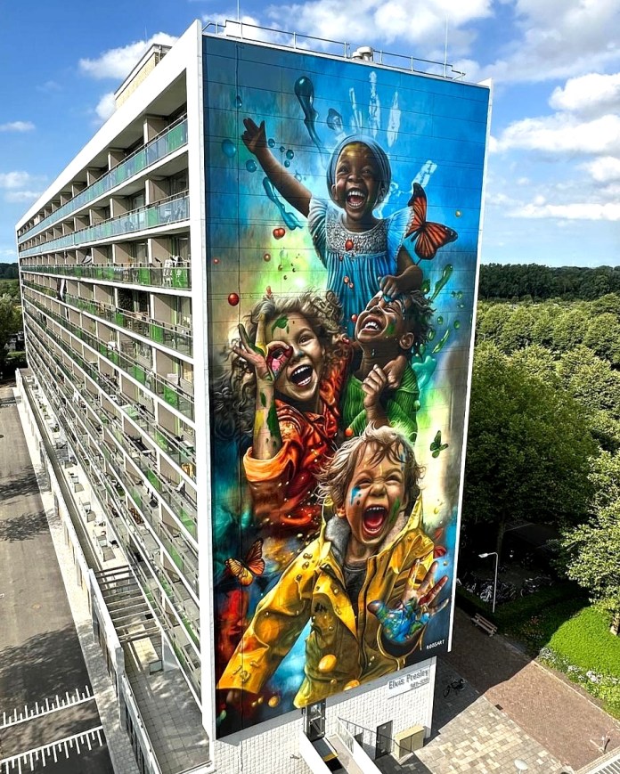 Tall residential building in Zwolle, Netherlands, with a vibrant mural of four joyful children laughing, surrounded by paint splashes, bubbles, butterflies, and marine elements by Rosalie de Graaf.