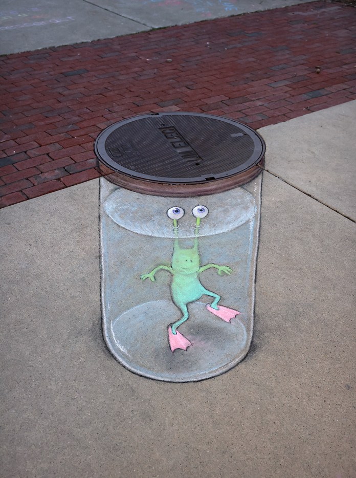 Chalk drawing on a sidewalk showing green cartoon character Sluggo trapped inside a large jar with the manhole as its lid, drawn by David Zinn.
