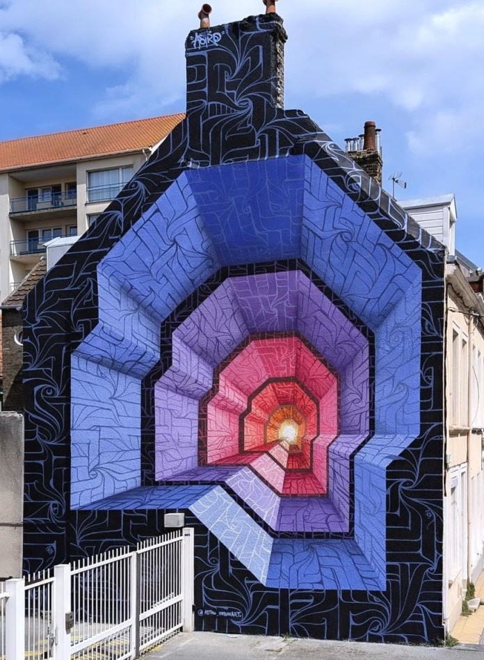 Large-scale optical illusion mural by ASTRO in Calais, France, showing a multicolored geometric tunnel in purple, pink, and red painted on the side of a gable house.
