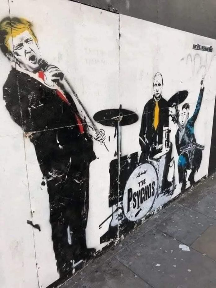Stencil street art of Trump with a mic, Putin on drums, and Kim Jong-un cheering. The drum kit reads “The Psychos” and the artist’s name “Loretto” appears in the top corner.