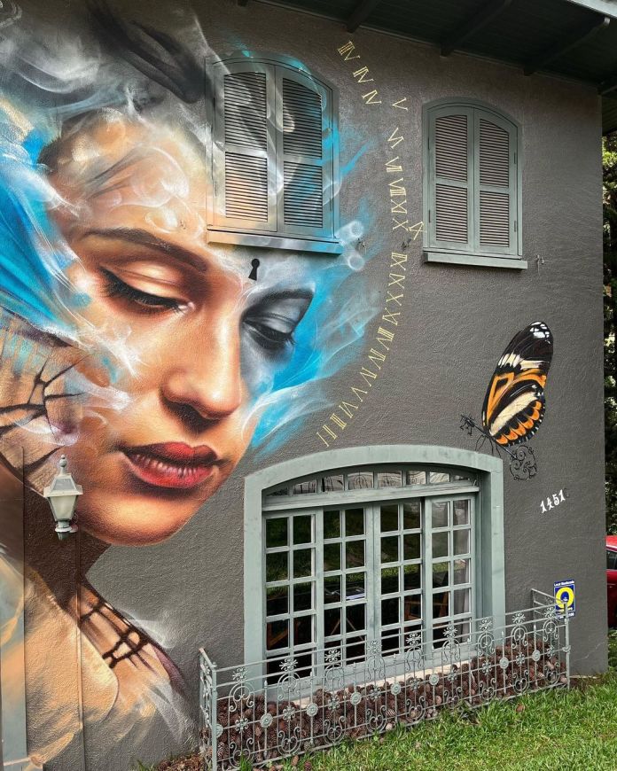 A striking mural by Filite in Curitiba, Brazil, showcasing a realistic face partially dissolving into butterfly wings, symbolizing transformation and movement through art.