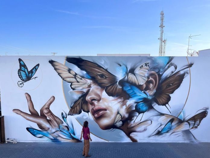 A mural by Filite in São Paulo, Brazil, featuring a woman’s face merging with butterflies in a blend of realism and abstract fluidity, symbolizing the theme of liberation.