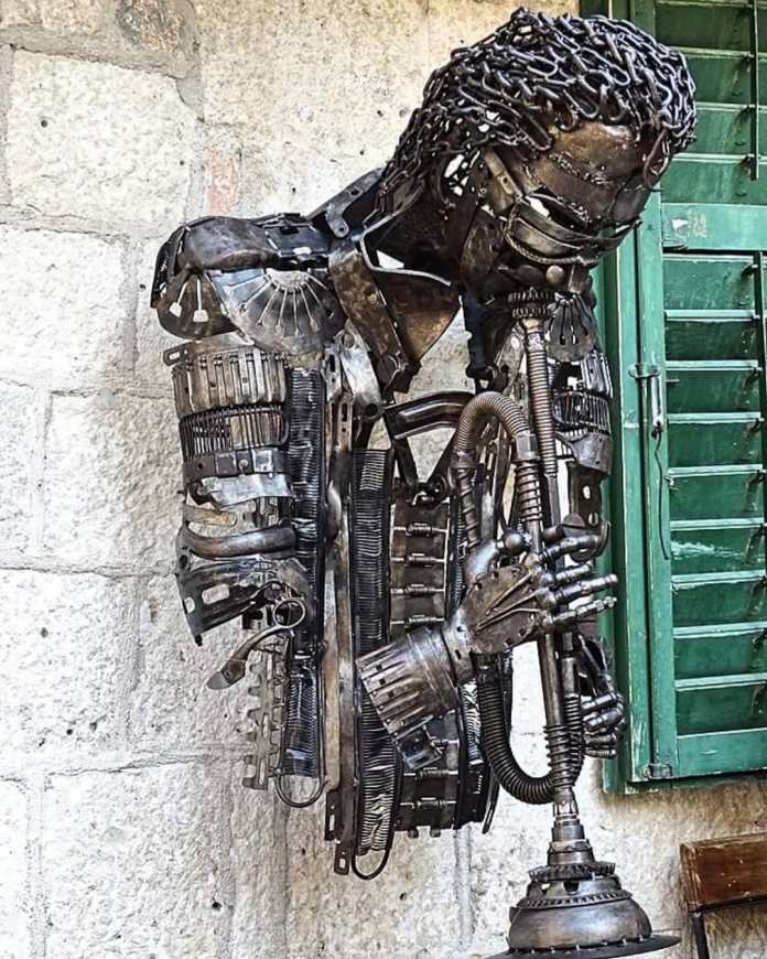 Sculpture of Miles Davis made from metal scraps and chains, playing a trumpet and mounted on a stone wall in Kotor Old Town, Montenegro.