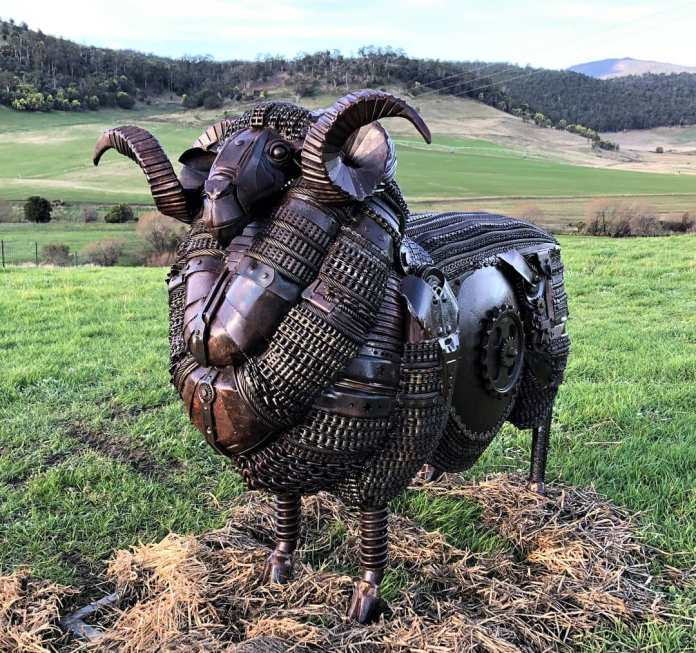 Metal sculpture of a Merino ram made from repurposed steel and machine parts, standing in a grassy field in Tasmania.