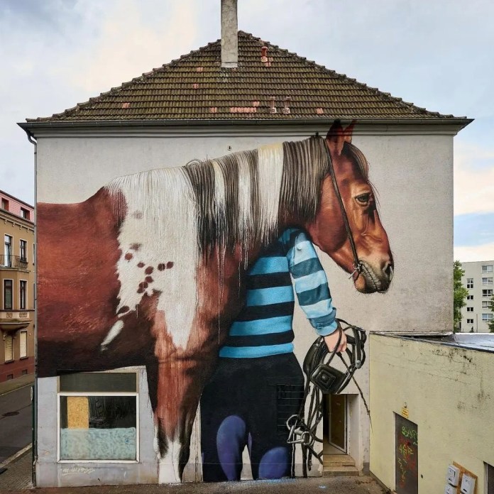 Mural by Matthias Mross in Neunkirchen, Germany, showing a child holding a camera with a horse’s body and head seamlessly replacing the child’s head and torso, painted on a tall white building.