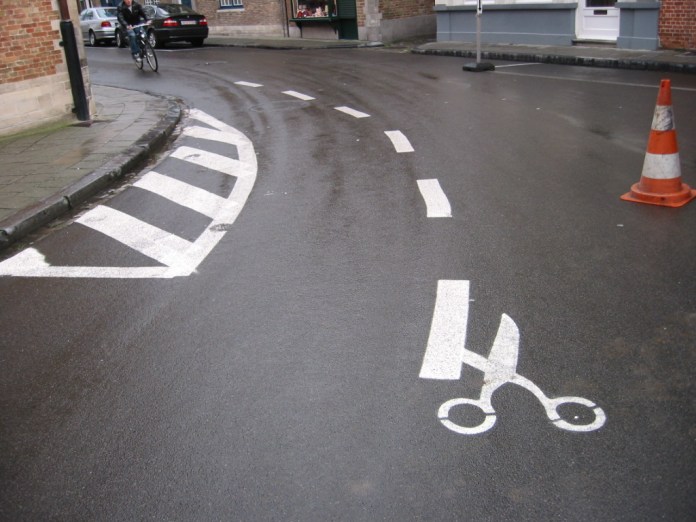 Creative road marking by Roadsworth showing scissors cutting the dashed lines.