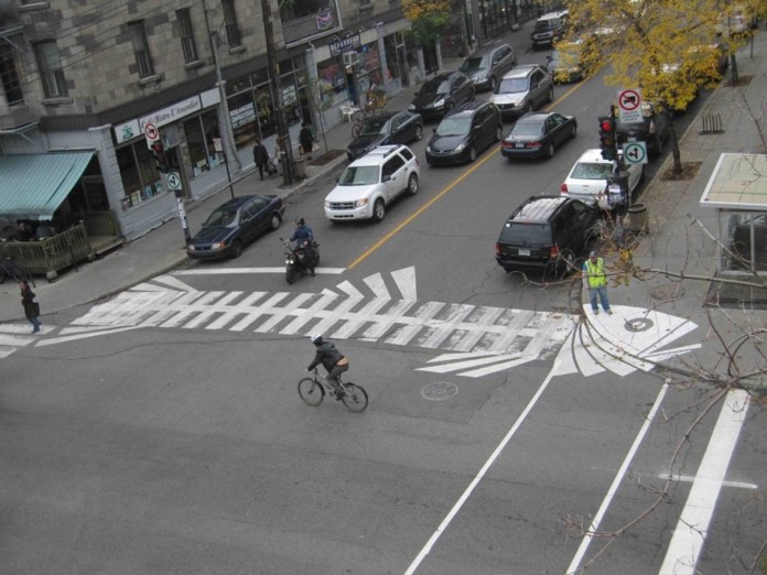 Innovative crosswalk art by Roadsworth designed to look like a fish skeleton on a city intersection.