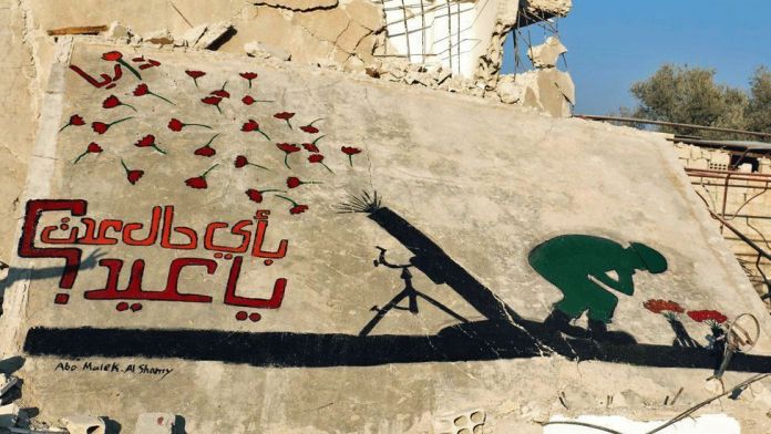 A powerful mural by Abu Malik al-Shami on the wall of a partially destroyed building in Darayya, Syria. The artwork depicts a green silhouette of a kneeling figure planting red flowers in front of a shadow of a mounted machine gun, symbolizing a transformation from war to peace. Above, red flowers appear to float away, contrasting with the surrounding destruction. Arabic text beside the image translates to, "With what spirit shall we celebrate Eid?" emphasizing the despair and loss faced during a time of supposed joy. The mural is signed "Abo Malik Al Shamy," highlighting the artist's poignant commentary on the cost of war.