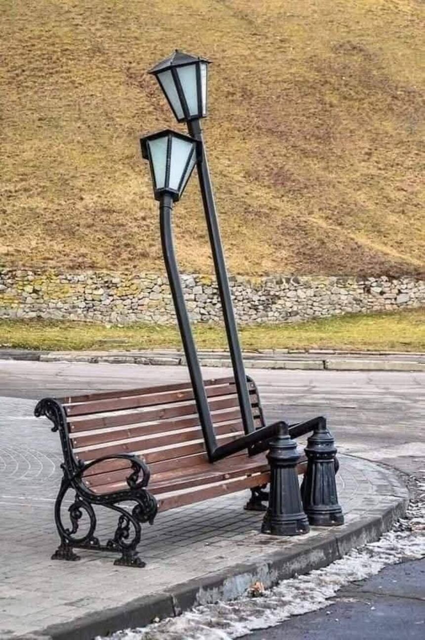 Sculpture of two street lamps hugging on a bench
