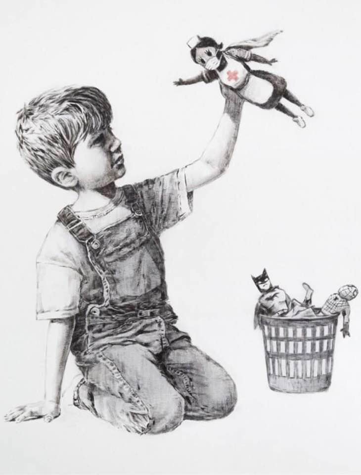 ‘Game Changer,’ a 2020 artwork by Banksy created as a tribute to NHS healthcare workers. The monochrome piece depicts a young boy in overalls, kneeling and lifting a nurse doll wearing a cape, face mask, and Red Cross emblem like a superhero. In the background, discarded superhero toys, including Batman and Spider-Man, lie in a wastebasket, symbolizing a shift in admiration towards real-life heroes during the COVID-19 pandemic.