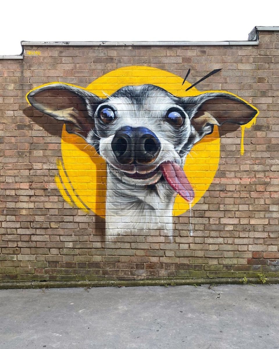 A playful mural by WOSKerski in Penge, South East London, featuring a cartoonish dog with exaggerated bulging eyes and its tongue sticking out. The bright yellow background adds a humorous and eye-catching element.