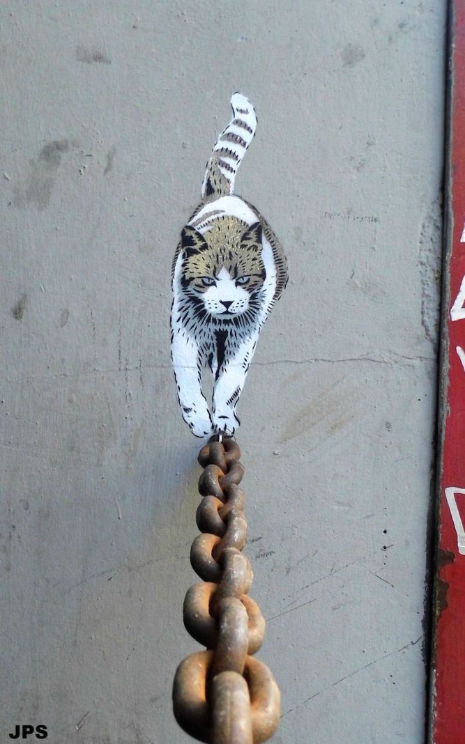 A realistic stencil street art piece of a black cat sitting on a ledge by graffiti artist JPS.