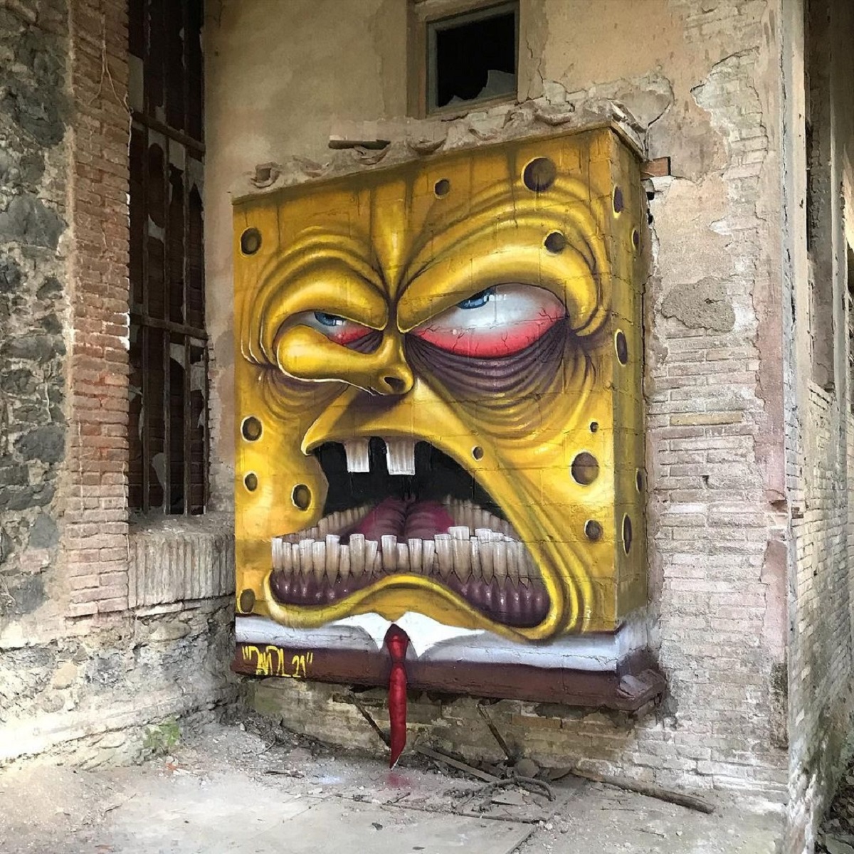 Post-graffiti artwork by DavidL featuring an aggressive and exaggerated depiction of SpongeBob SquarePants with sharp teeth and menacing eyes, painted on a distressed wall of an abandoned building, located outside Barcelona, Spain.