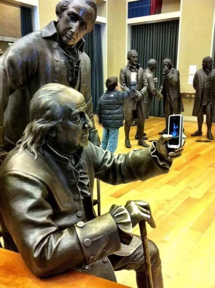 Men posing for a selfie with life-size bronze Founding Fathers street art statues by Studio EIS in Philadelphia, USA. Interactive public graffiti and 3D illusion fun.