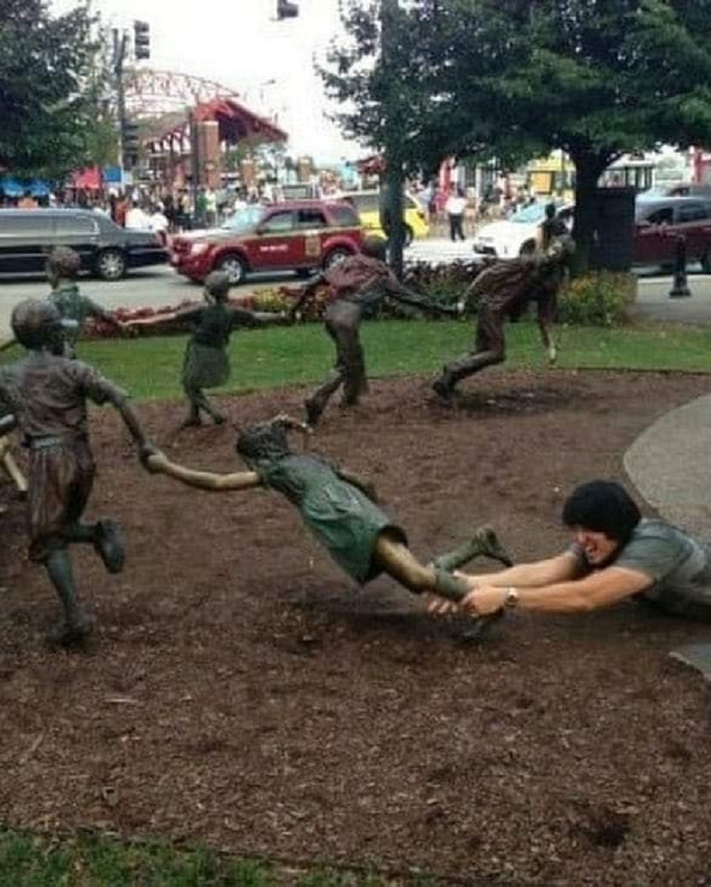 Women happily join a circle of dancing bronze children statues. This interactive street art and 3D illusion brings public graffiti and murals to life.