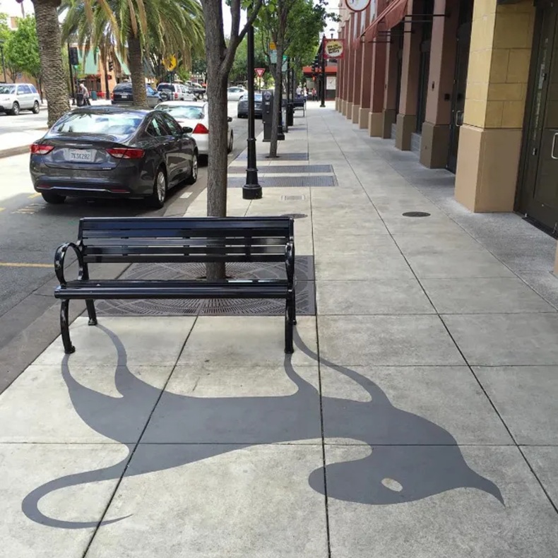 A fake shadow painted on the pavement making a bike rack look like a cute monster